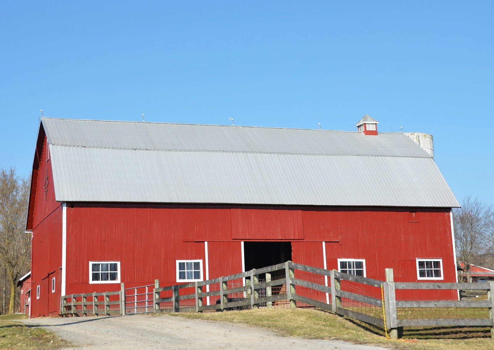 A red barn stands under a bright blue sky.